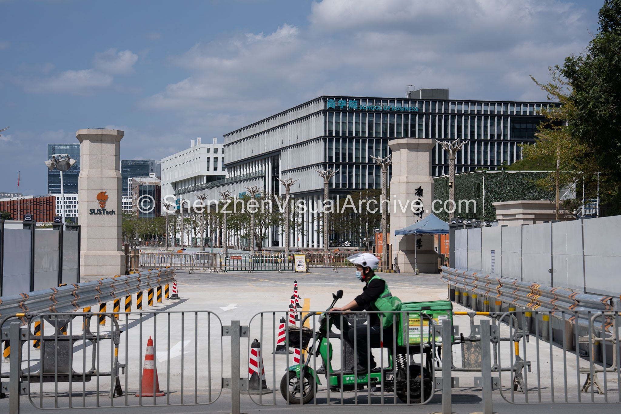 Urban Rhythm: Courier Passing the SUSTech Main Gate at Nanshan (SVA-26-0160)